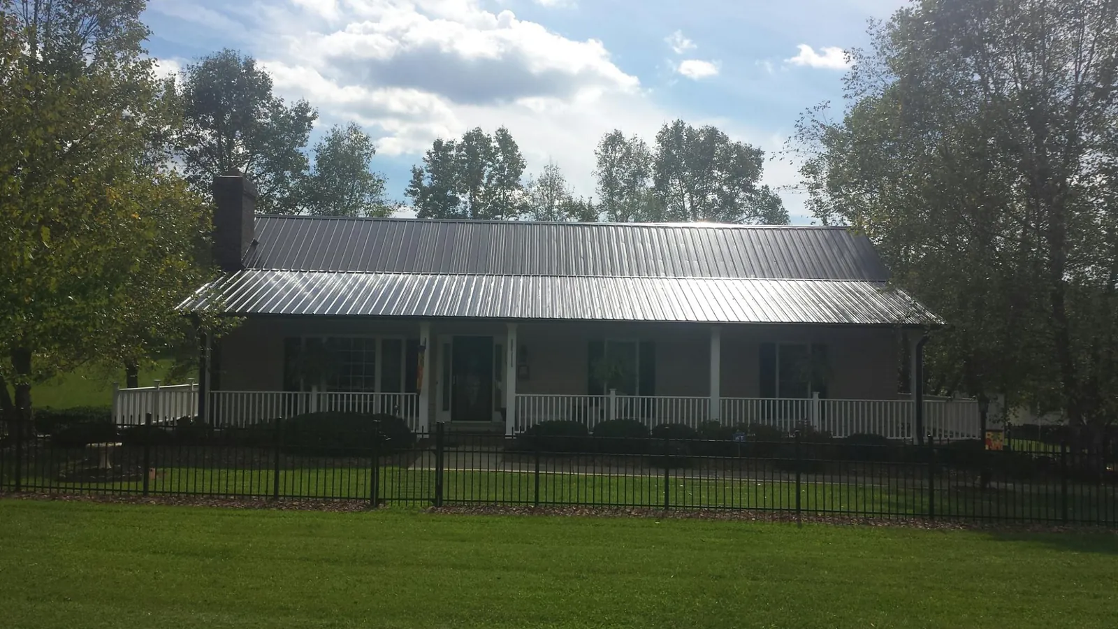 Gray metal roof on a brick ranch with a full width front porch — Gutter Guard Installation work by our crew in Red Lake Falls