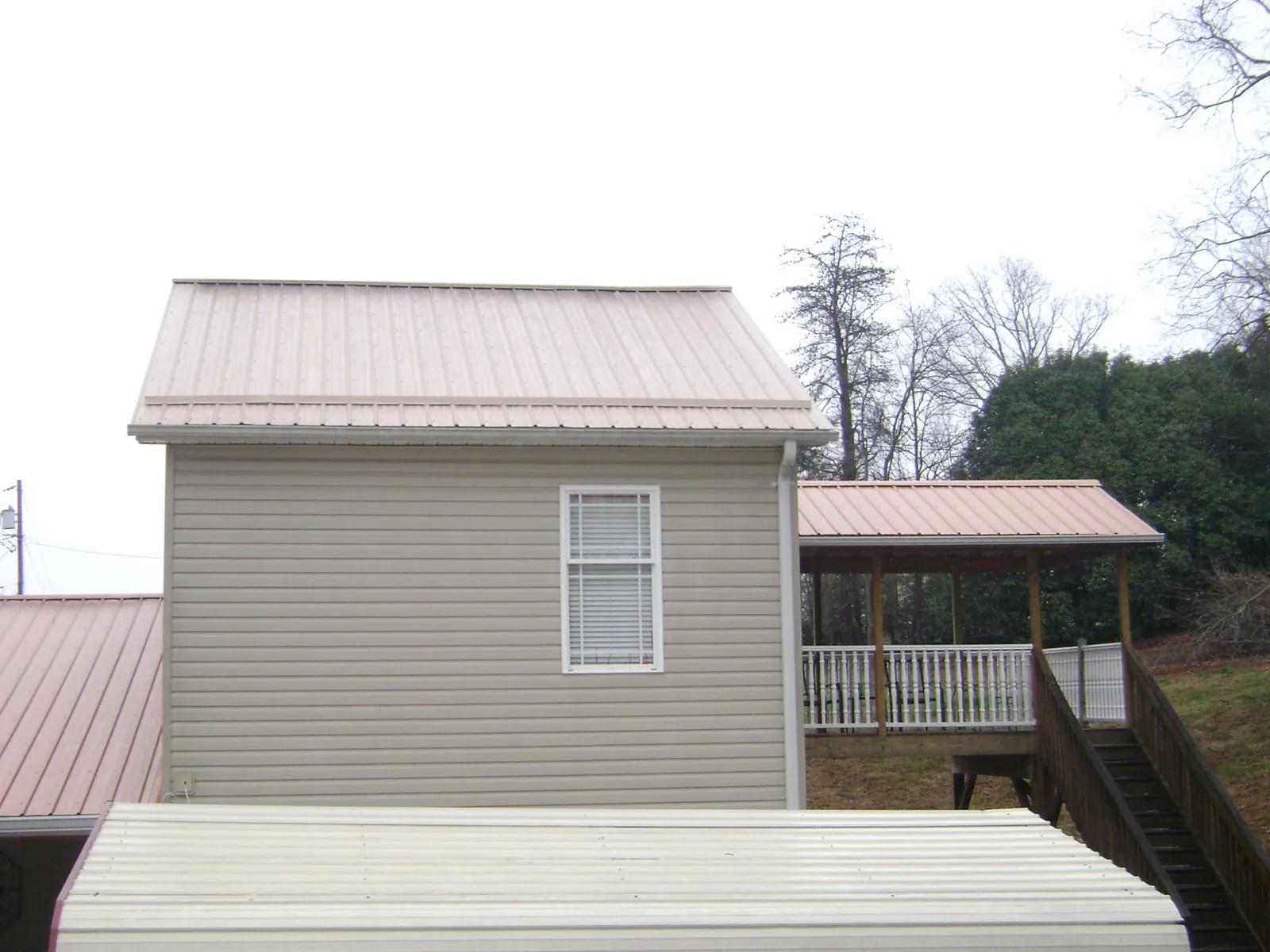 Tan metal roofs on a two story addition and attached porch in Red Lake Falls