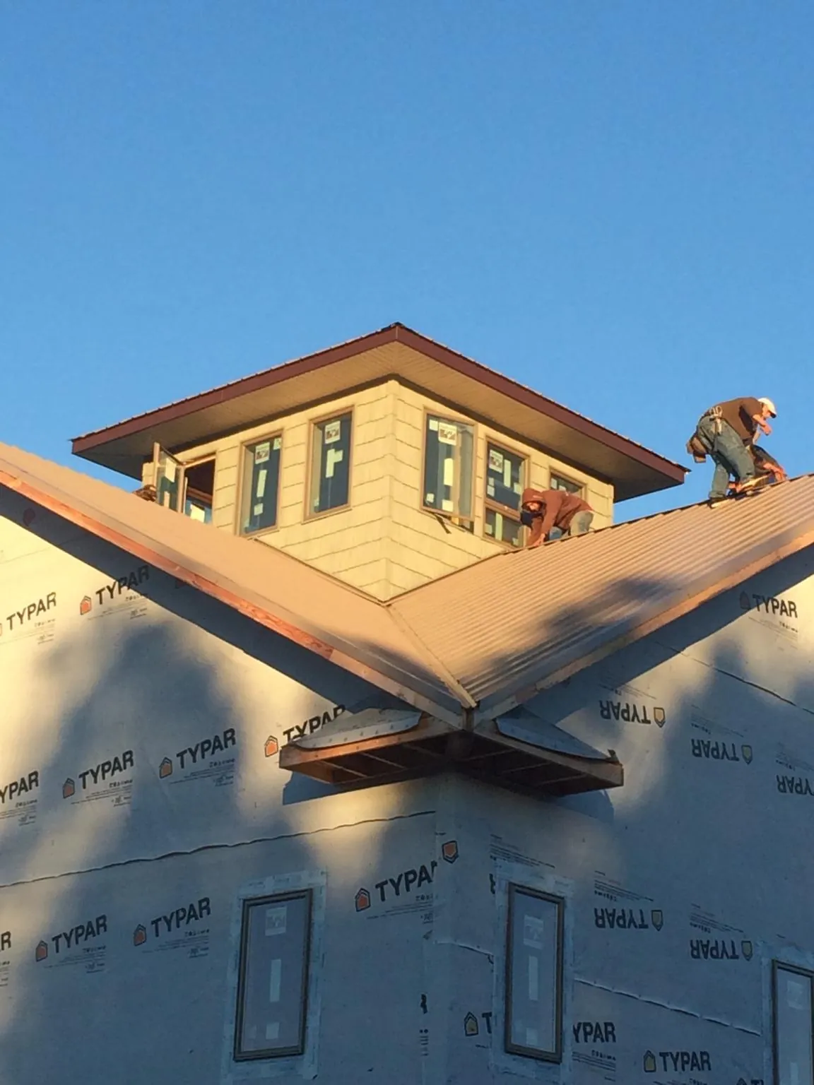 Roofers working around a rooftop cupola on a new metal roof at sunset — Roof Waterproofing in Red Lake Falls by Roofing Brothers
